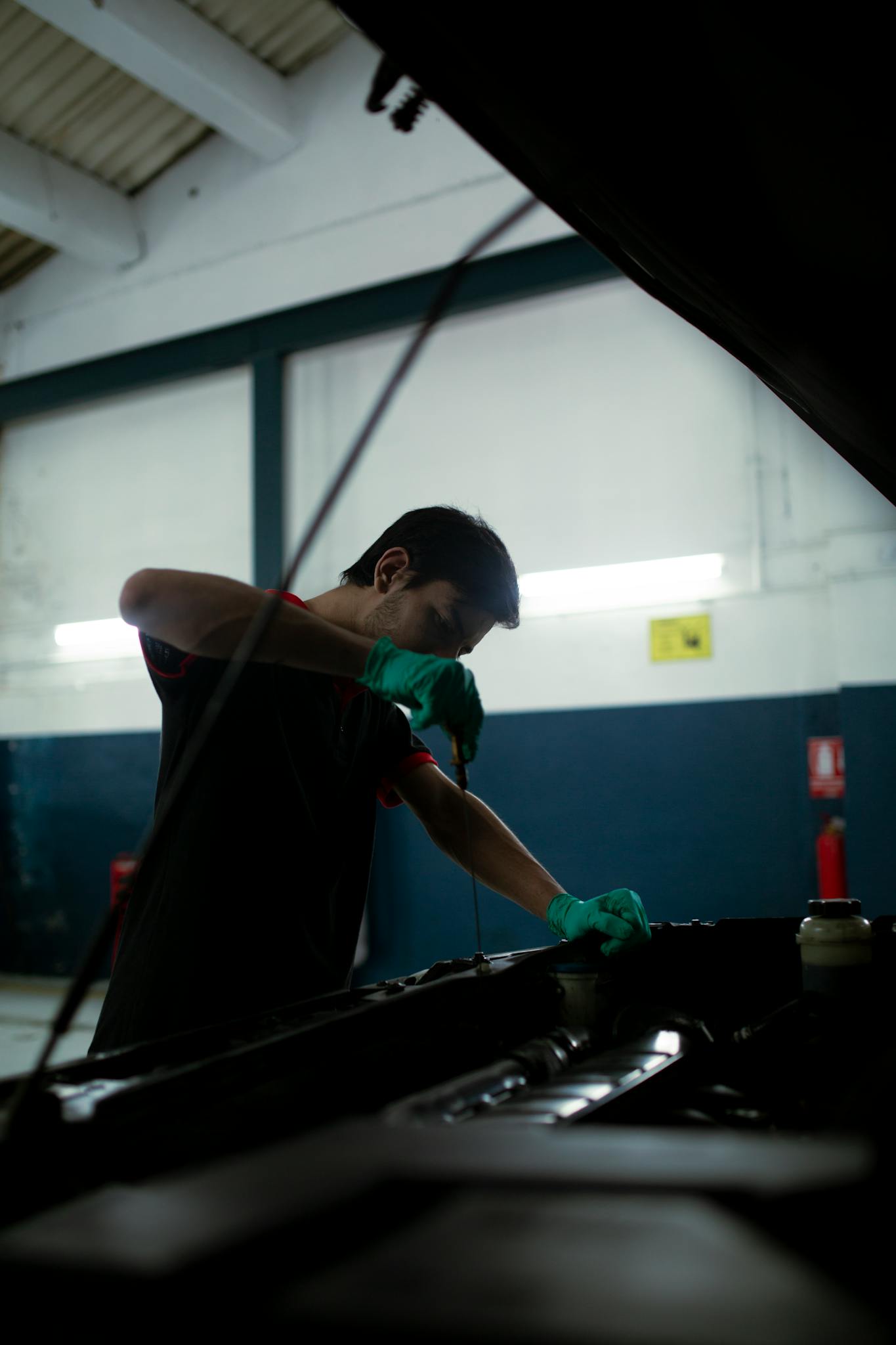 mechanic checks engine oil in a car